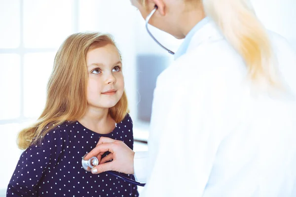 Médico examinando a un niño paciente por estetoscopio. Linda niña en la cita con el médico. Concepto de medicina. Foto tonificada —  Fotos de Stock