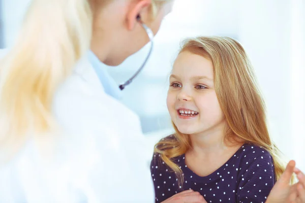 Arzt untersucht eine Kinderpatientin mit einem Stethoskop. Nettes kleines Mädchen beim Arzttermin. Medizinkonzept. Getöntes Foto — Stockfoto