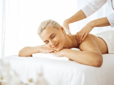 Güzel sarışın kadın kapalı gözlerle sırt masajından hoşlanıyor. Spa salonu konsepti