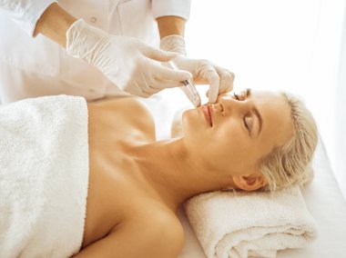 Güzellik uzmanı elleri şırıngayla kadın yüzüne güzellik prosedürü uyguluyor. Kozmetik tıp ve cerrahi, güzellik enjeksiyonları konsepti