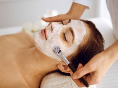 Güzel esmer kadın kapalı gözlerle kozmetik maske takmaktan zevk alıyor. Tıp ve kaplıca merkezi kavramlarında rahatlatıcı tedavi