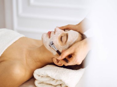 Güzel esmer kadın kapalı gözlerle kozmetik maske takmaktan zevk alıyor. Tıp ve kaplıca merkezi kavramlarında rahatlatıcı tedavi