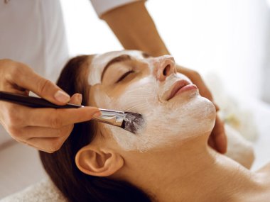 Güzel esmer kadın kapalı gözlerle kozmetik maske takmaktan zevk alıyor. Tıp ve kaplıca merkezi kavramlarında rahatlatıcı tedavi