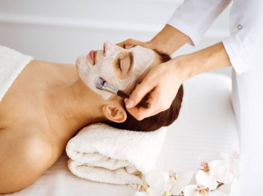 Güzel esmer kadın kapalı gözlerle kozmetik maske takmaktan zevk alıyor. Tıp ve kaplıca merkezi kavramlarında rahatlatıcı tedavi