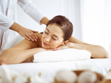 Güzel esmer kadın gözleri kapalı sırt masajından hoşlanıyor. Spa ve tıp konsepti