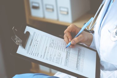 Hastanedeki kadın doktor. Genç kadın doktor hastane ofisinde otururken reçete yazıyor ya da form dolduruyor.