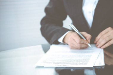 Sözleşme belgesini kalemle teslim eden kimliği belirsiz kadın elleri. Anlaşma imzalama veya iş konsepti