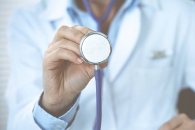Bilinmeyen doktor kadın steteskop başı tutuyor, yakın plan. Doktor hastayı muayene etmeye ve yardım etmeye hazır. Sağlık hizmetleri, en iyi tedavi ve tıp konseptinde yardım ve sigorta