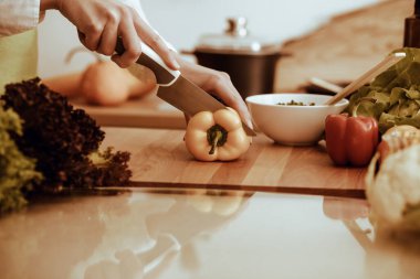 Mutfakta pişen bilinmeyen insan elleri. Sarı dolma biber dilimleyen kadın. Sağlıklı yemek ve vejetaryen gıda konsepti.