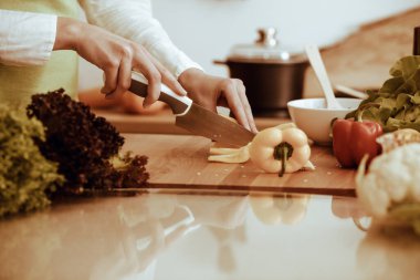 Mutfakta pişen bilinmeyen insan elleri. Sarı dolma biber dilimleyen kadın. Sağlıklı yemek ve vejetaryen gıda konsepti.