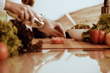 Mutfakta pişen bilinmeyen insan elleri. Kırmızı domatesleri dilimleyen kadın. Sağlıklı yemek ve vejetaryen gıda konsepti.