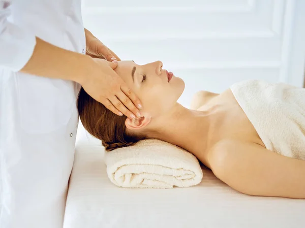 Bella donna godendo massaggio facciale con gli occhi chiusi. concetto di trattamento termale in medicina — Foto Stock