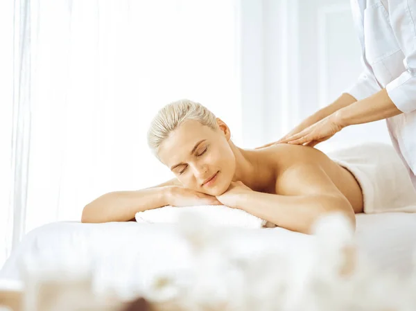 Hermosa mujer rubia disfrutando de masaje de espalda con los ojos cerrados. concepto de salón de spa — Foto de Stock