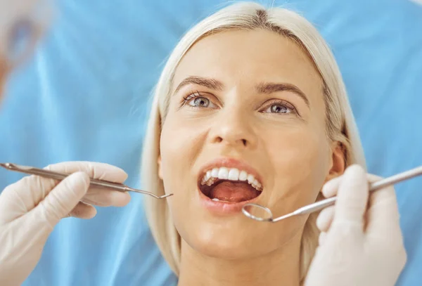 Uśmiechnięta blondynka badana przez dentystę w klinice dentystycznej. Zdrowe zęby i koncepcja medycyny — Zdjęcie stockowe