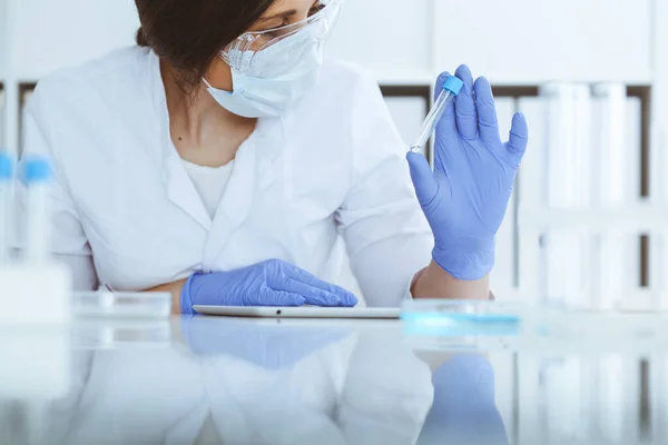 Close-up de cientista profissional feminino em óculos de proteção fazendo experiência com reagentes em laboratório. Medicina e conceito de pesquisa — Fotografia de Stock