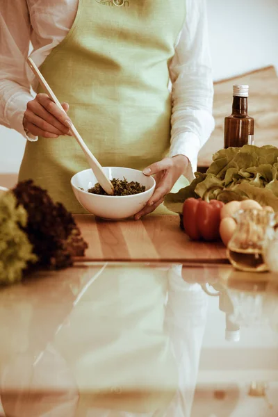 Неизвестные человеческие руки готовят на кухне. Женщина занята овощным салатом. Здоровое питание и вегетарианское питание — стоковое фото