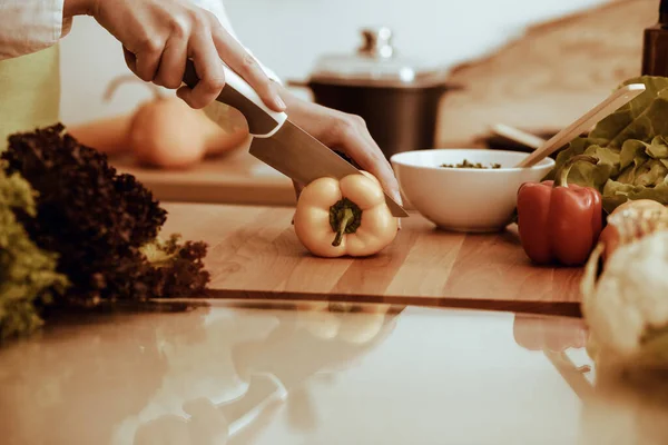 모르는 인간 손으로 부엌에서 요리하고 있어. 노란 종 후추를 썰고 있는 여성. 건강에 좋은 식사와 채식 식품의 개념 — 스톡 사진