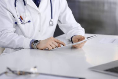 Bilinmeyen erkek doktor klinikteki tablet bilgisayarla yakın planda çalışıyor. İşteki genç doktor. Mükemmel sağlık hizmeti, tıp konsepti