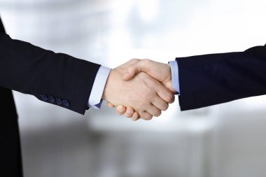İş adamları el sıkışıyor, yakın plan. Modern bir ofiste duran bir grup tanınmamış iş adamı. Takım çalışması, ortaklık ve el sıkışma kavramı