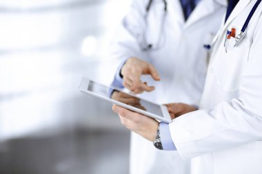 Steteskoplu kimliği belirsiz iki doktor muayene sonuçlarını tartışıyorlar, hastane ofisinde duruyorlar. Doktorlar ilaç kayıtlarını doldurmak için bir bilgisayar tableti kullanıyorlar. Mükemmel tıbbi servis.