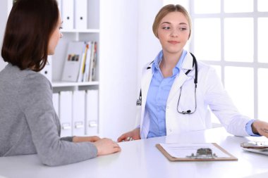 Hastane muayenehanesindeki genç kadın doktor ve hasta. Terapistin mavi renkli bluzu iyi görünüyor. Tıp ve sağlık hizmetleri kavramı