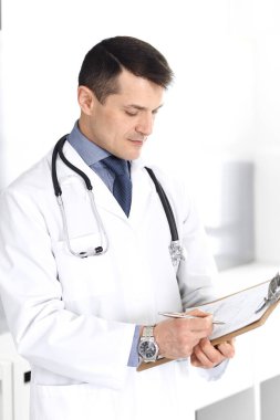 Doktor, ilaç kayıtlarını doldurmak için pano kullanıyor. Klinikte mükemmel bir tıbbi hizmet. Hastanede çalışan bir doktor. Tıp ve sağlık hizmetleri kavramları