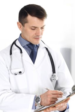 Doktor, ilaç kayıtlarını doldurmak için pano kullanıyor. Klinikte mükemmel bir tıbbi hizmet. Hastanede çalışan bir doktor. Tıp ve sağlık hizmetleri kavramları