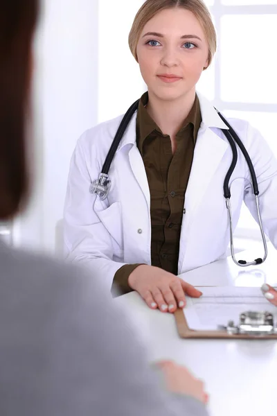 Junge Ärztin und Patientin bei der ärztlichen Untersuchung im Krankenhaus. Die khakifarbene Bluse des Therapeuten sieht gut aus. Medizin, Gesundheitswesen und Arztterminkonzept — Stockfoto