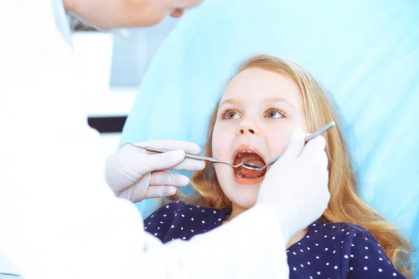 Menina sentada na cadeira dentária com a boca aberta durante o check-up oral, enquanto médico. Consulta ao dentista. Conceito de medicina. Foto tonificada — Fotografia de Stock