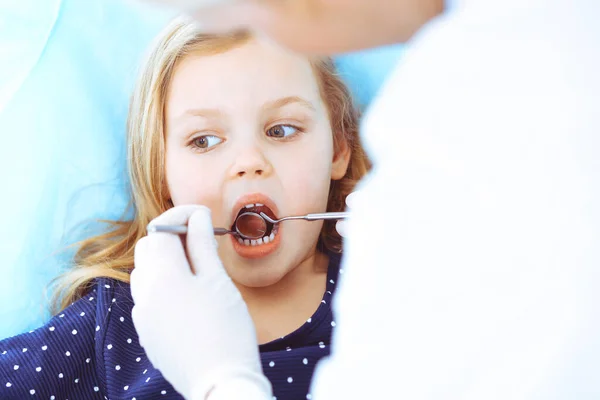 Mała dziewczynka siedzi na krześle dentystycznym z otwartymi ustami podczas kontroli doustnej, podczas gdy lekarz. Odwiedzam gabinet dentystyczny. Koncepcja medyczna. Uszkodzone zdjęcie — Zdjęcie stockowe