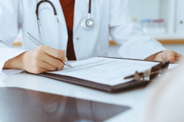 Bilinmeyen kadın-doktor hastaya danışmanlık yaparken başvuru formu dolduruyor. Tıp konsepti