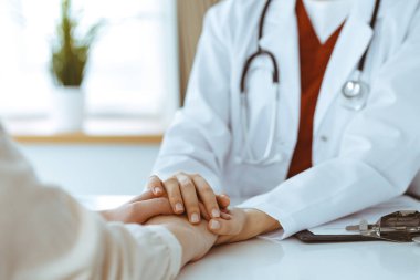 Kadın hastasına güvence veren kimliği belirsiz kadın doktorun elleri, yakın plan. Tıp konsepti