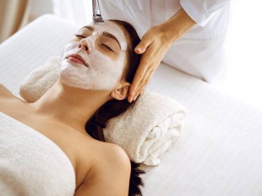 Güzel esmer kadın kapalı gözlerle kozmetik maske takmaktan zevk alıyor. Tıp ve kaplıca merkezi kavramlarında rahatlatıcı tedavi