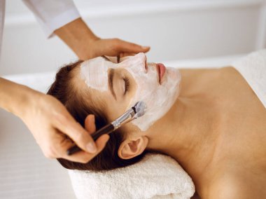 Güzel esmer kadın kapalı gözlerle kozmetik maske takmaktan zevk alıyor. Tıp ve kaplıca merkezi kavramlarında rahatlatıcı tedavi