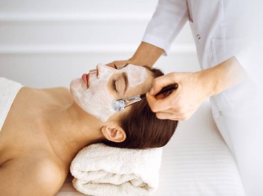 Güzel esmer kadın kapalı gözlerle kozmetik maske takmaktan zevk alıyor. Tıp ve kaplıca merkezi kavramlarında rahatlatıcı tedavi