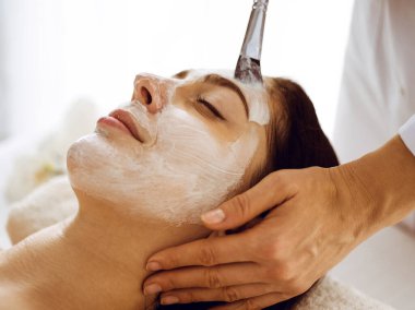 Güzel esmer kadın kapalı gözlerle kozmetik maske takmaktan zevk alıyor. Tıp ve kaplıca merkezi kavramlarında rahatlatıcı tedavi