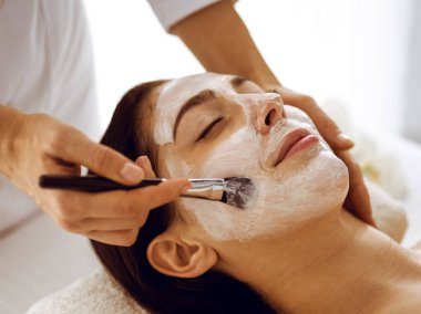 Güzel esmer kadın kapalı gözlerle kozmetik maske takmaktan zevk alıyor. Tıp ve kaplıca merkezi kavramlarında rahatlatıcı tedavi