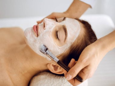 Güzel esmer kadın kapalı gözlerle kozmetik maske takmaktan zevk alıyor. Tıp ve kaplıca merkezi kavramlarında rahatlatıcı tedavi