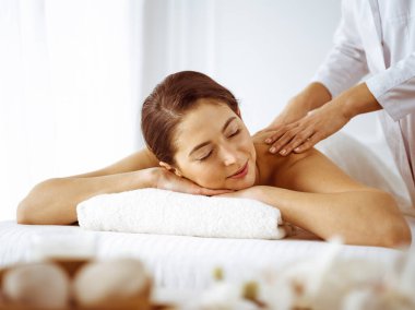 Güzel esmer kadın gözleri kapalı sırt masajından hoşlanıyor. Spa ve tıp konsepti