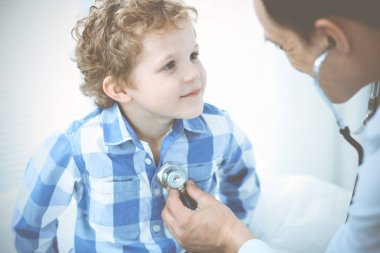 Doktor ve sabırlı çocuk. Doktor küçük çocuğu muayene ediyor. Kliniğe düzenli tıbbi ziyaret. İlaç ve sağlık hizmetleri kavramı