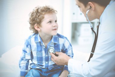 Doktor ve sabırlı çocuk. Doktor küçük çocuğu muayene ediyor. Kliniğe düzenli tıbbi ziyaret. İlaç ve sağlık hizmetleri kavramı