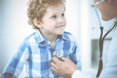 Doktor ve sabırlı çocuk. Doktor küçük çocuğu muayene ediyor. Kliniğe düzenli tıbbi ziyaret. İlaç ve sağlık hizmetleri kavramı