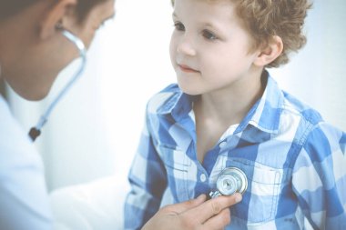 Doktor ve sabırlı çocuk. Doktor küçük çocuğu muayene ediyor. Kliniğe düzenli tıbbi ziyaret. İlaç ve sağlık hizmetleri kavramı