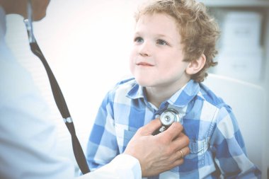Doktor ve sabırlı çocuk. Doktor küçük çocuğu muayene ediyor. Kliniğe düzenli tıbbi ziyaret. İlaç ve sağlık hizmetleri kavramı