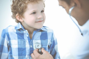 Doktor ve sabırlı çocuk. Doktor küçük çocuğu muayene ediyor. Kliniğe düzenli tıbbi ziyaret. İlaç ve sağlık hizmetleri kavramı