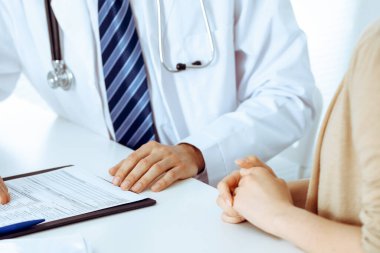 Doktor ve hasta kadın hastane ofisindeki masada bir şey tartışıyorlar. Tıp etiği kavramları ve tıp alanında insanlara yardım
