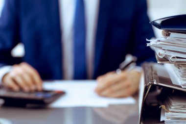Dosyalarda işadamı ya da muhasebeci tarafından işleme konmayı bekleyen dosyalar var. Muhasebe bütçesi. Denetim, sigorta ve iş konsepti