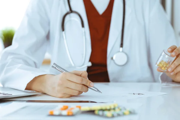 Unknown woman-doctor fills up prescription form. close-up. Panacea and life save, prescribe treatment, legal drug store. Medicine concept