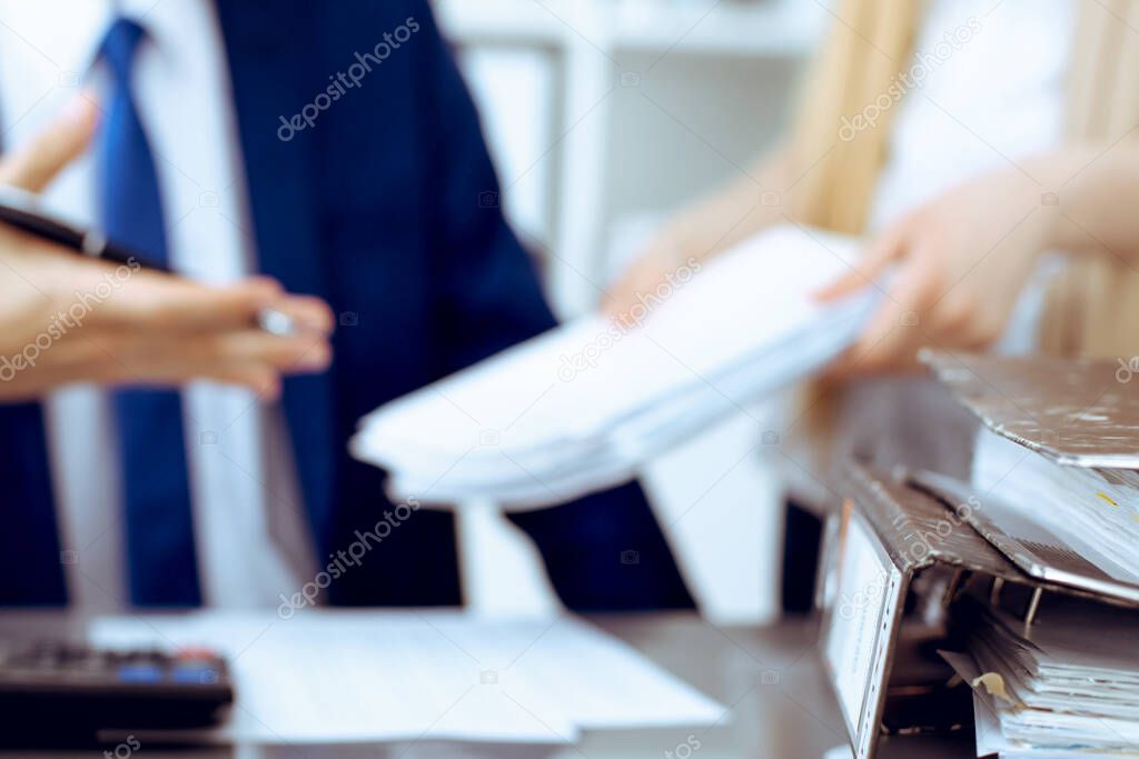 Binders with papers waiting to be processed with businessman or bookkeeper back in blur. Accounting planning budget. Audit, insurance and business concept