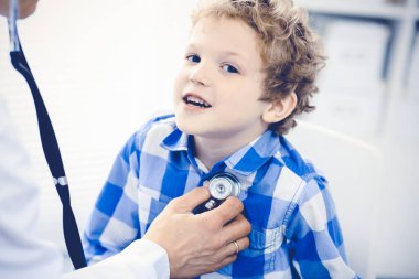 Doktor ve sabırlı çocuk. Doktor küçük çocuğu muayene ediyor. Kliniğe düzenli tıbbi ziyaret. İlaç ve sağlık hizmetleri kavramı